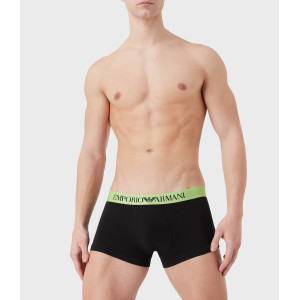 Modelo masculino cuerpo entero parte frontal con calzoncillo boxer negro con cinta verde acido y la leyenda EMPORIO ARMANI .